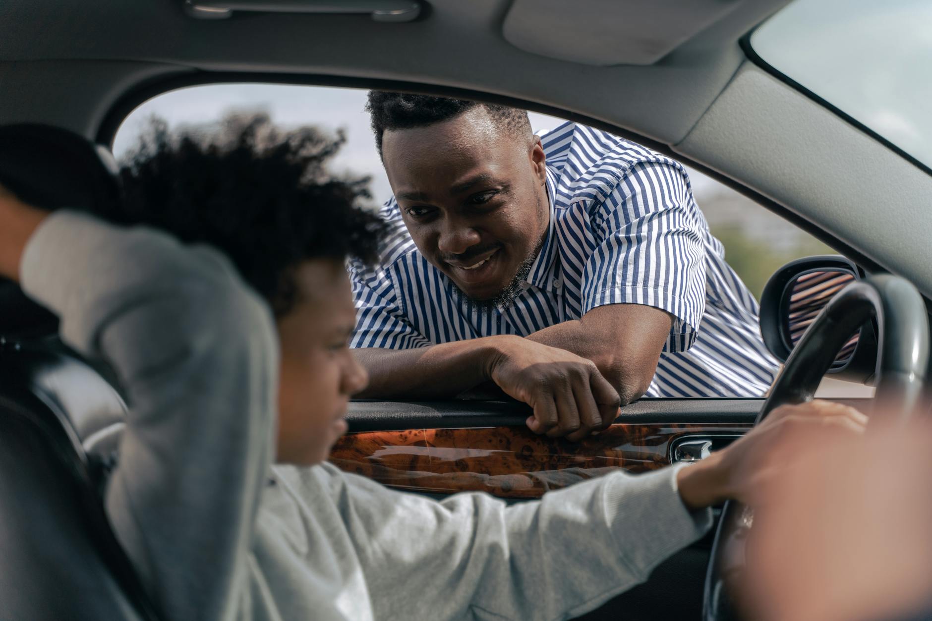 man in white and blue striped dress shirt sitting on car seat